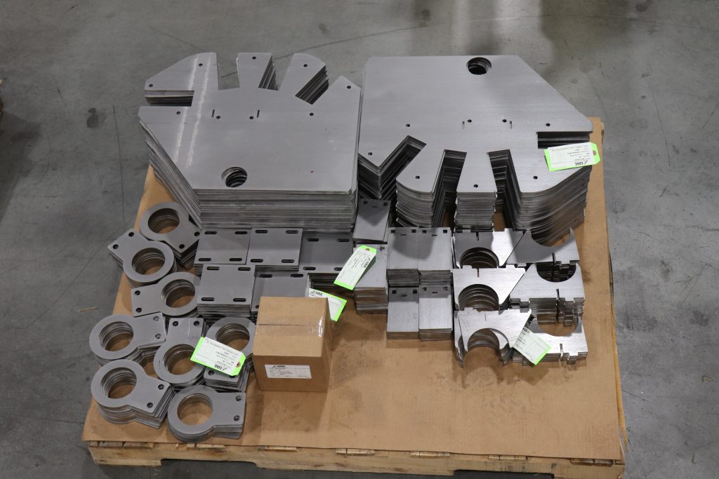 Various piles of finished laser parts stacked on a pallet.