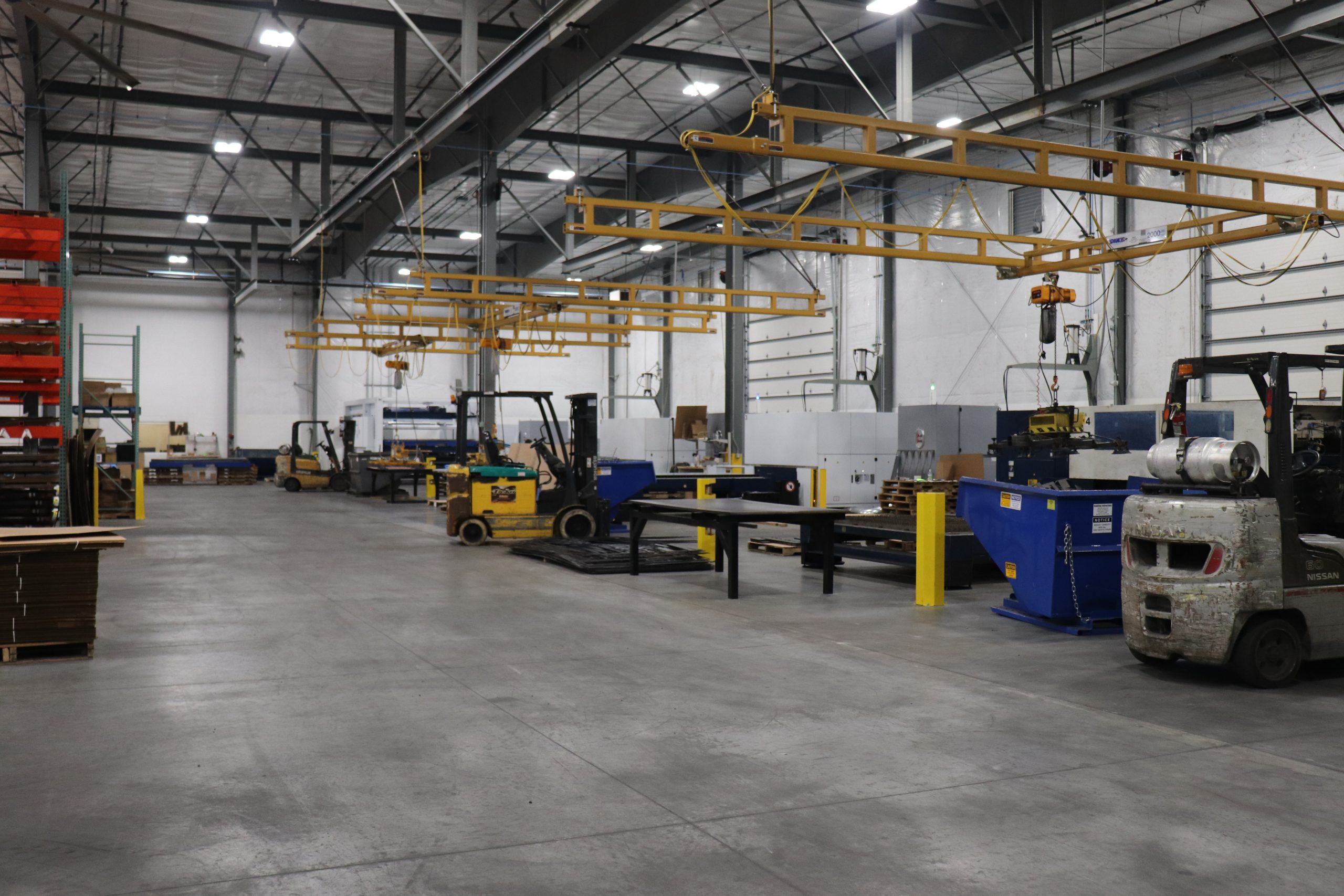 Inside view of Edge Metalworks' pristine warehouse with laser machinery and forklifts.