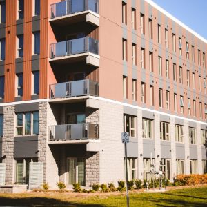 Apartment building with brown metal and light colored stone siding.